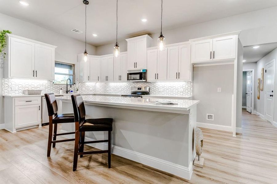 Kitchen featuring white cabinets, a kitchen island, stainless steel appliances, and light wood-type flooring