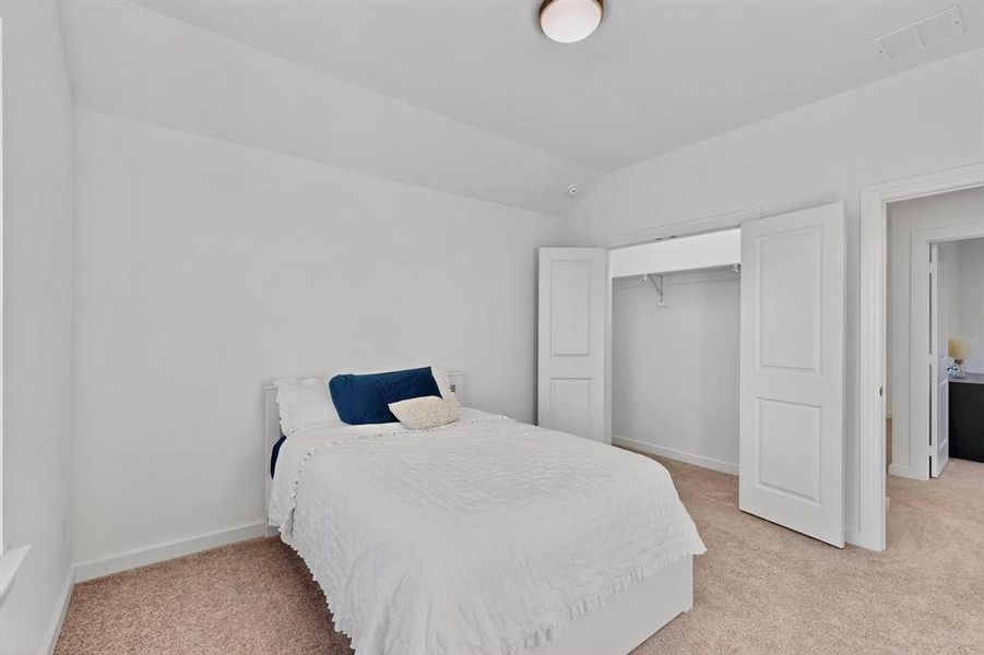 Bedroom featuring vaulted ceiling, light colored carpet, and a closet Bedroom featuring vaulted ceiling, light colored carpet, and a closet