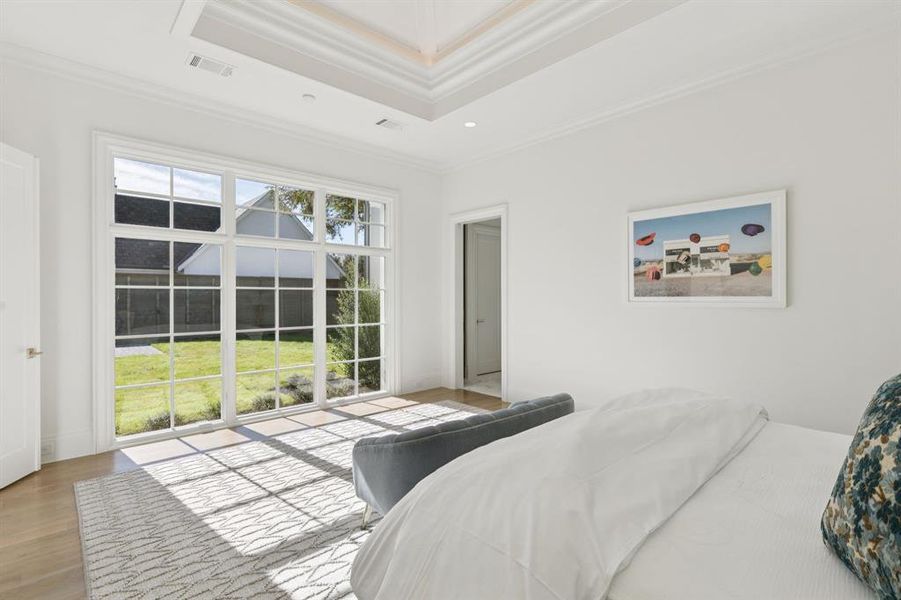 Bedroom with ornamental molding, wood finished floors, a raised ceiling, and recessed lighting