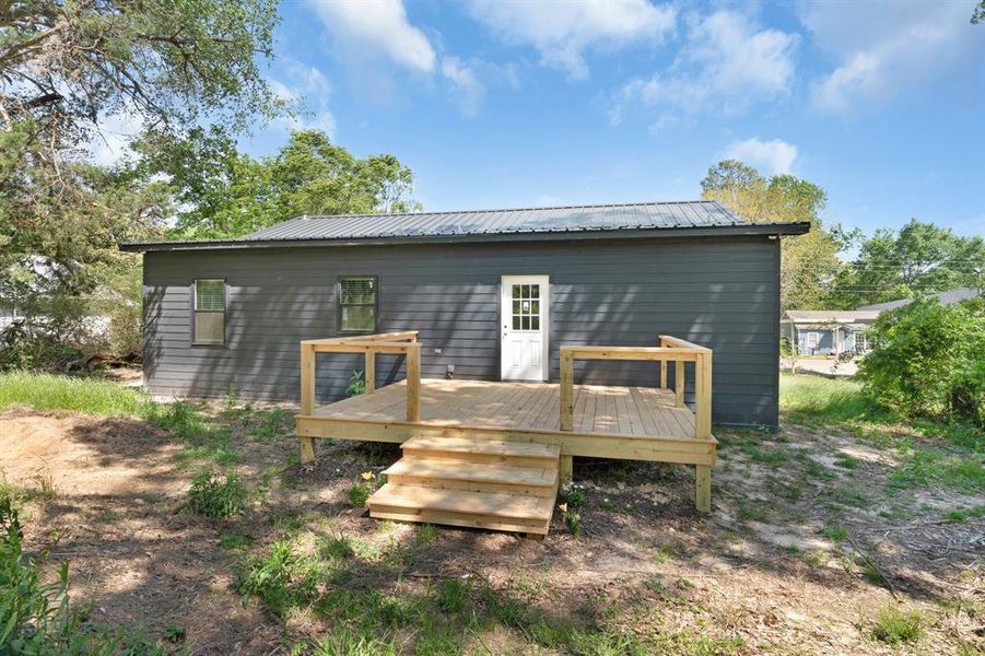 Rear view of house with a wooden deck and metal roof Rear view of house with a wooden deck and metal roof