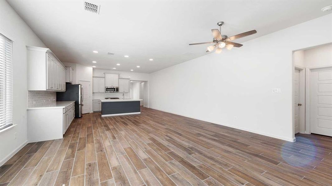 Kitchen featuring backsplash, stainless steel appliances, ceiling fan, white cabinetry, and a kitchen island