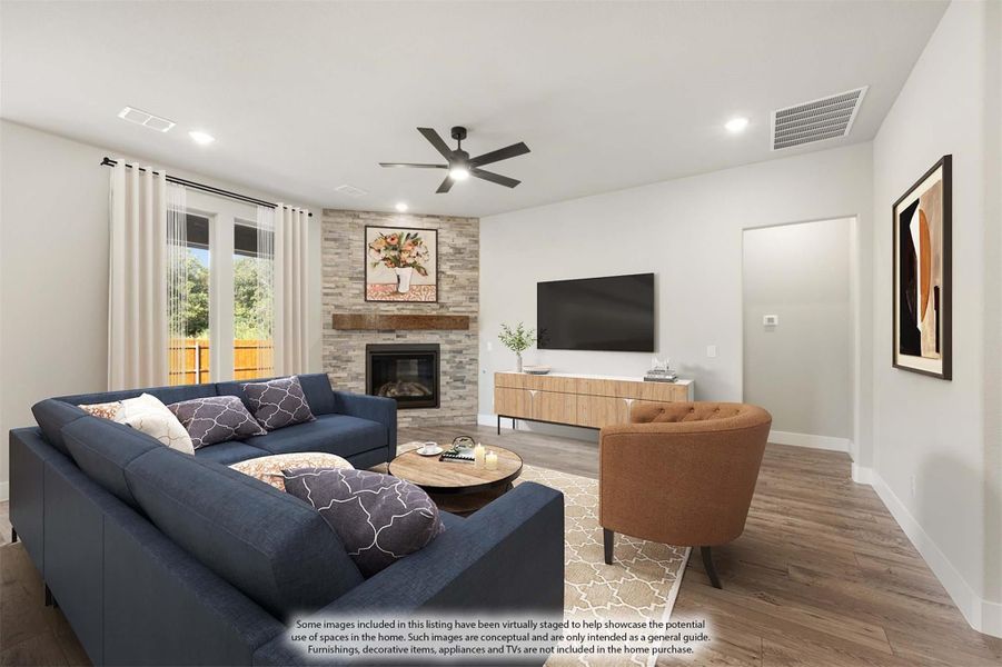 Living room with stone fireplace, navy sectional sofa, hardwood floors, and ceiling fan