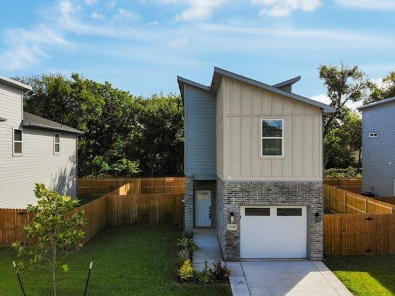 Contemporary home with brick siding, board and batten siding, an attached garage, and driveway Contemporary home with brick siding, board and batten siding, an attached garage, and driveway