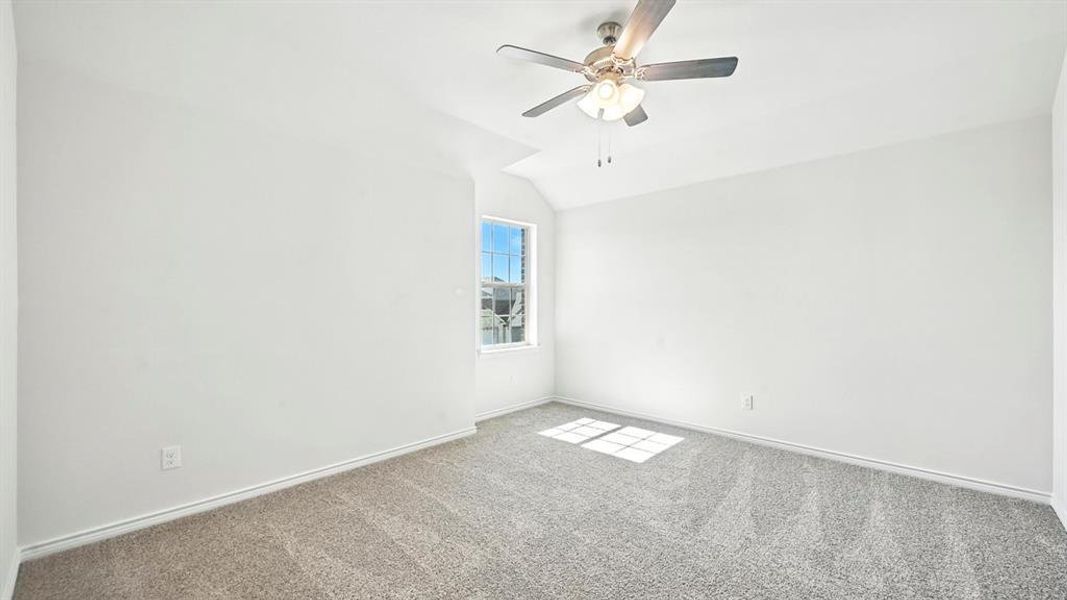 Carpeted empty room with vaulted ceiling and ceiling fan