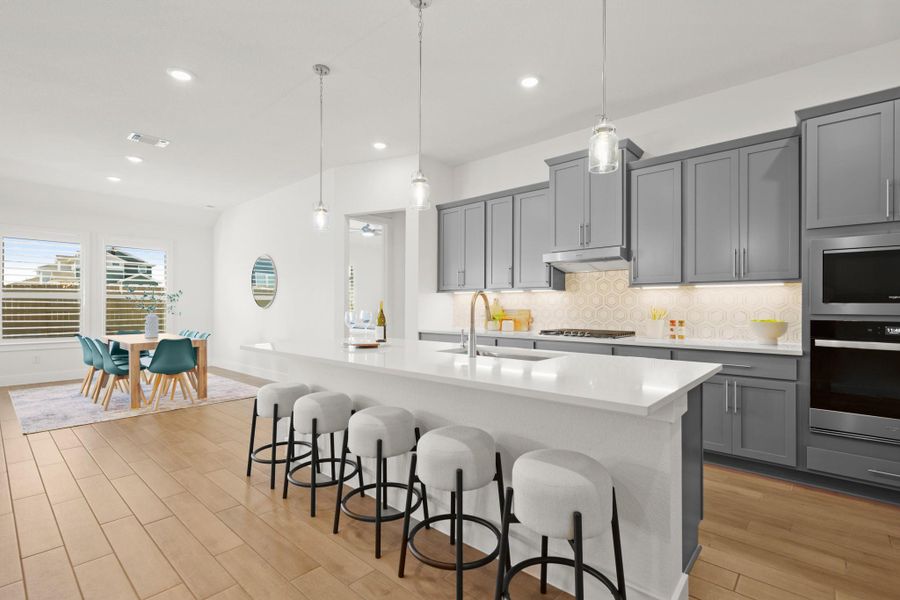Kitchen featuring tasteful backsplash, pendant lighting, gray cabinetry, a kitchen bar, and appliances with stainless steel finishes