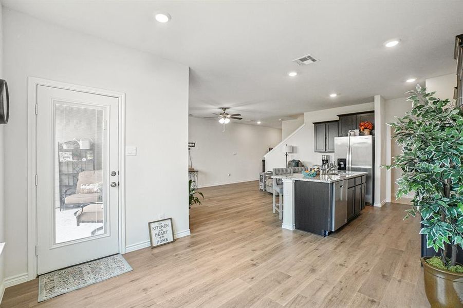 Kitchen with an island with sink, recessed lighting, light wood finished floors, a kitchen breakfast bar, and light stone countertops Kitchen with an island with sink, recessed lighting, light wood finished floors, a kitchen breakfast bar, and light stone countertops
