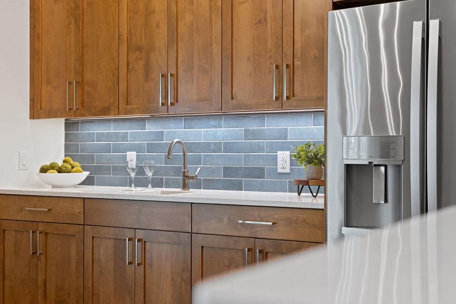 Kitchen with stainless steel fridge with ice dispenser, a sink, backsplash, and light countertops Kitchen with stainless steel fridge with ice dispenser, a sink, backsplash, and light countertops