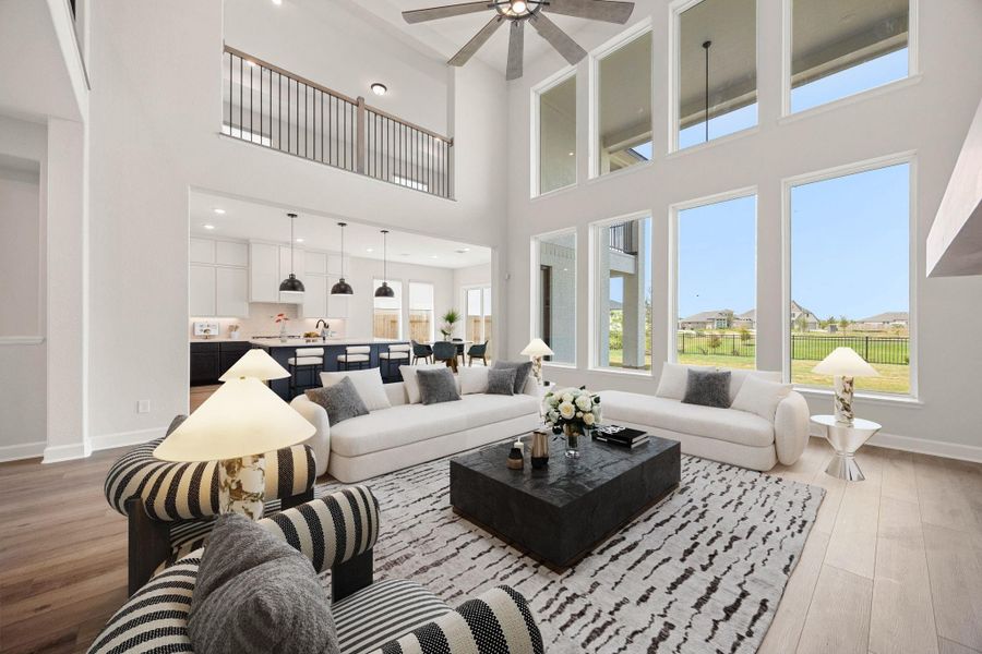Breathtaking two-story family room showcasing a magnificent wall of windows that floods the home with natural light and frames serene backyard views. This spectacular open-concept space features soaring double-height ceilings, a modern ceiling fan, and premium wide-plank flooring. The open layout seamlessly connects to the gourmet kitchen and offers a direct view of the upstairs game room catwalk, making it the ultimate hub for daily living and grand-scale entertaining. *Virtually Staged Breathtaking two-story family room showcasing a magnificent wall of windows that floods the home with natural light and frames serene backyard views. This spectacular open-concept space features soaring double-height ceilings, a modern ceiling fan, and premium wide-plank flooring. The open layout seamlessly connects to the gourmet kitchen and offers a direct view of the upstairs game room catwalk, making it the ultimate hub for daily living and grand-scale entertaining. *Virtually Staged