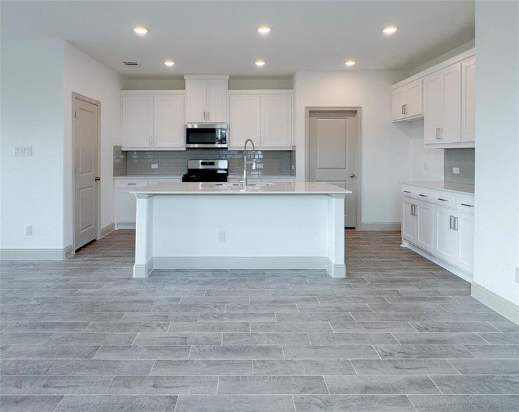 Kitchen with white cabinetry, light countertops, appliances with stainless steel finishes, and a sink