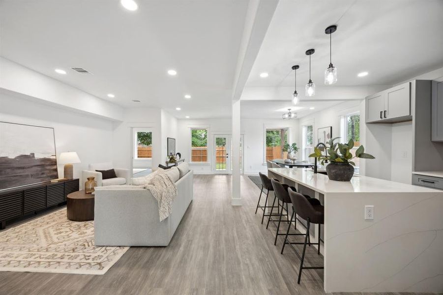 Living room with wood-style floors, open to the kitchen, dining area and back patio