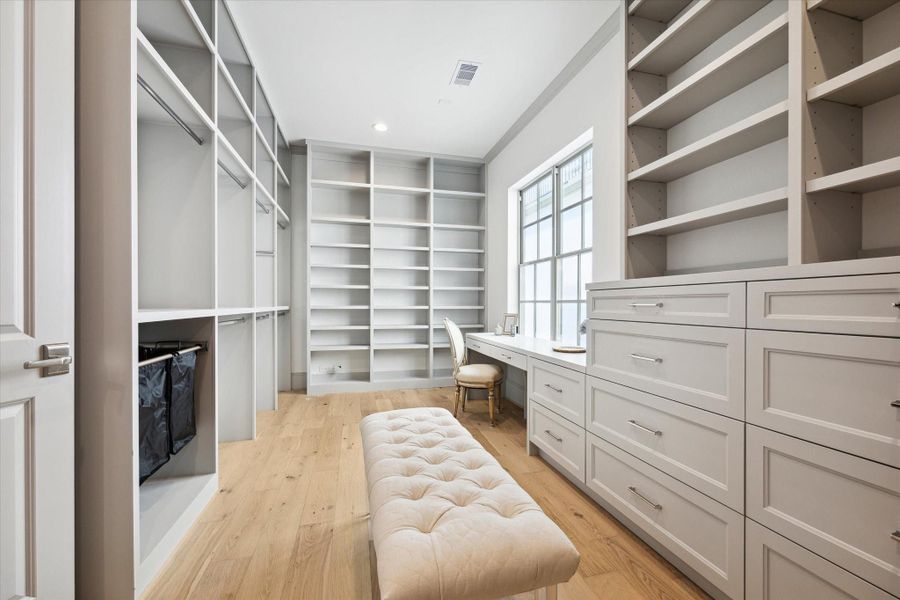 Upgraded custom Her closet with abundant handing space, banks of drawers and shelving, complete with vanity at window.