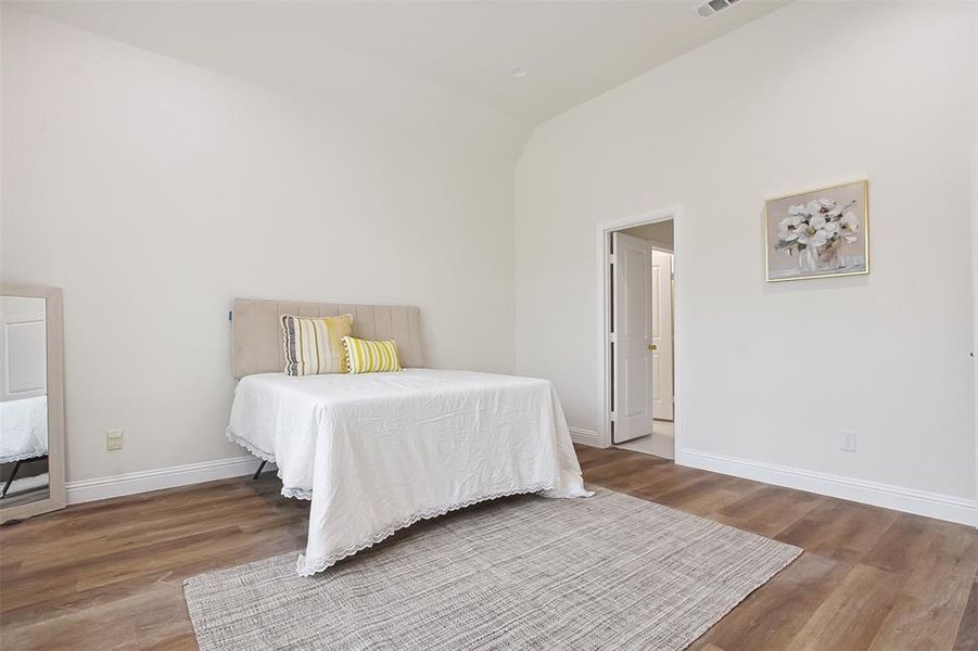 Bedroom featuring hardwood / wood-style floors and high vaulted ceiling