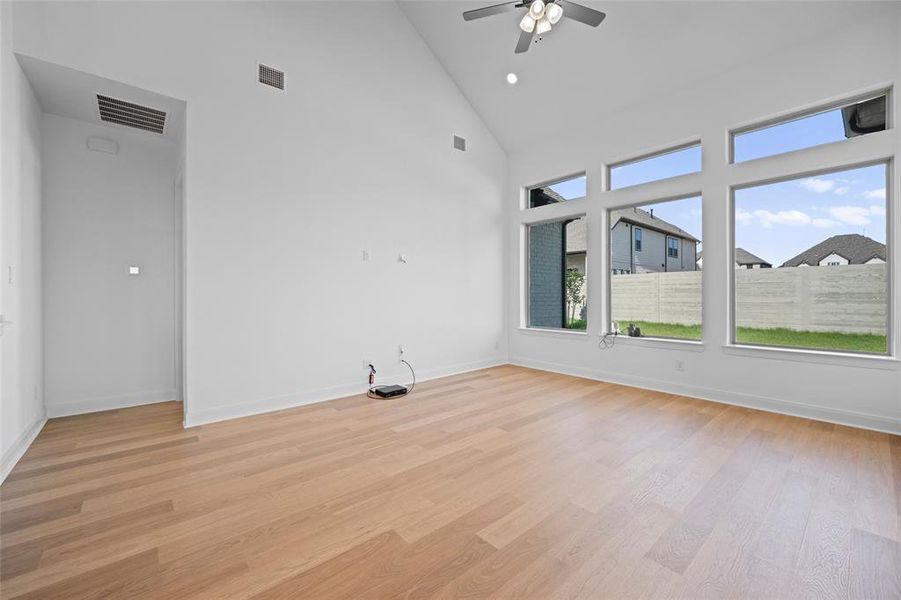 Spare room with light wood-type flooring, high vaulted ceiling, and ceiling fan