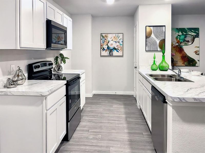 Kitchen with a sink, light wood-type flooring, dishwasher, range with electric stovetop, and a peninsula