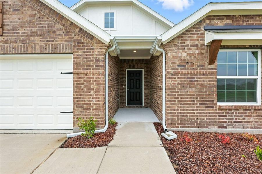Entrance to property with brick siding, a garage, and concrete driveway