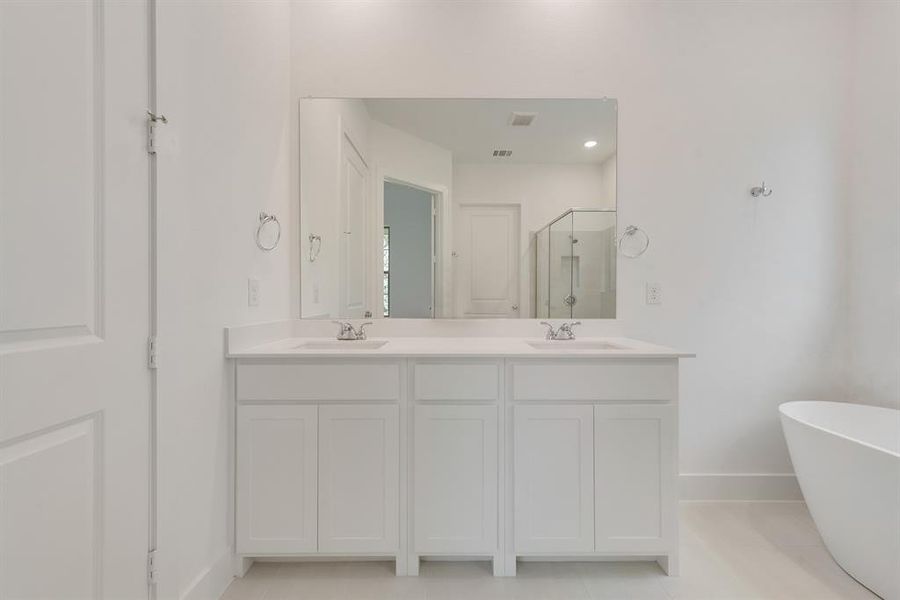 Full bath featuring a stall shower, double vanity, a freestanding tub, and light tile patterned floors Full bath featuring a stall shower, double vanity, a freestanding tub, and light tile patterned floors