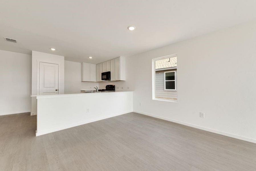 Kitchen with visible vents, baseboards, light wood-style flooring, black appliances, and white cabinetry