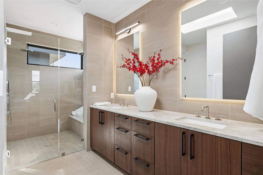 A sleek, contemporary bathroom features a spacious glass-enclosed shower and a long vanity with dual sinks.