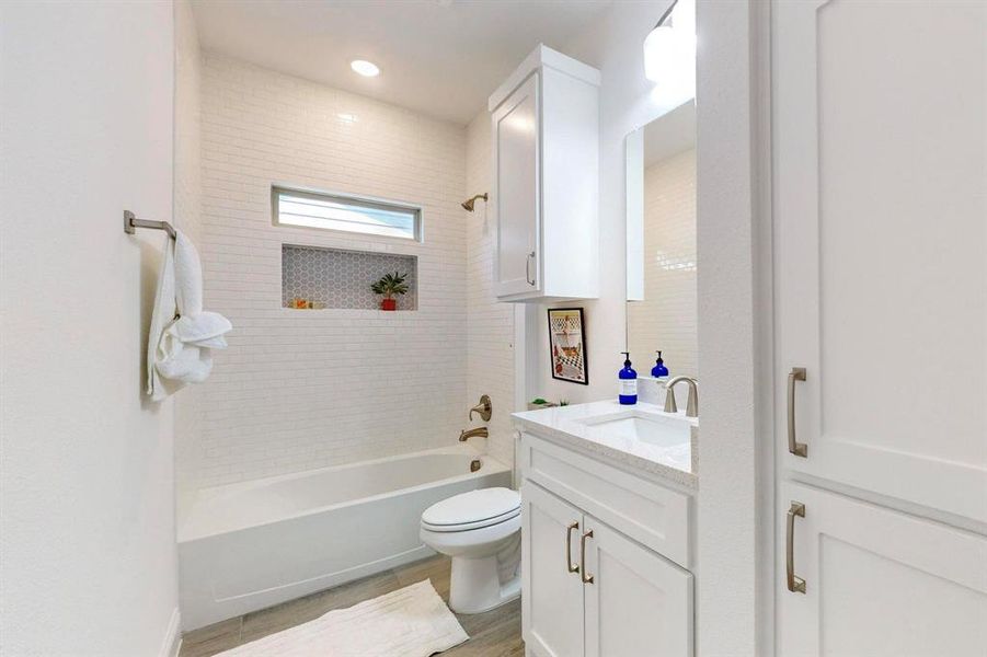 Hall Full bathroom featuring toilet, tiled shower / bath, and vanity