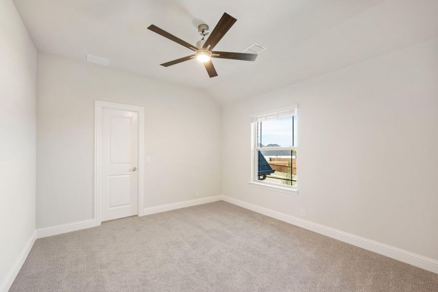 Empty bedroom with gray carpet, ceiling fan, white walls, and a single window Empty bedroom with gray carpet, ceiling fan, white walls, and a single window