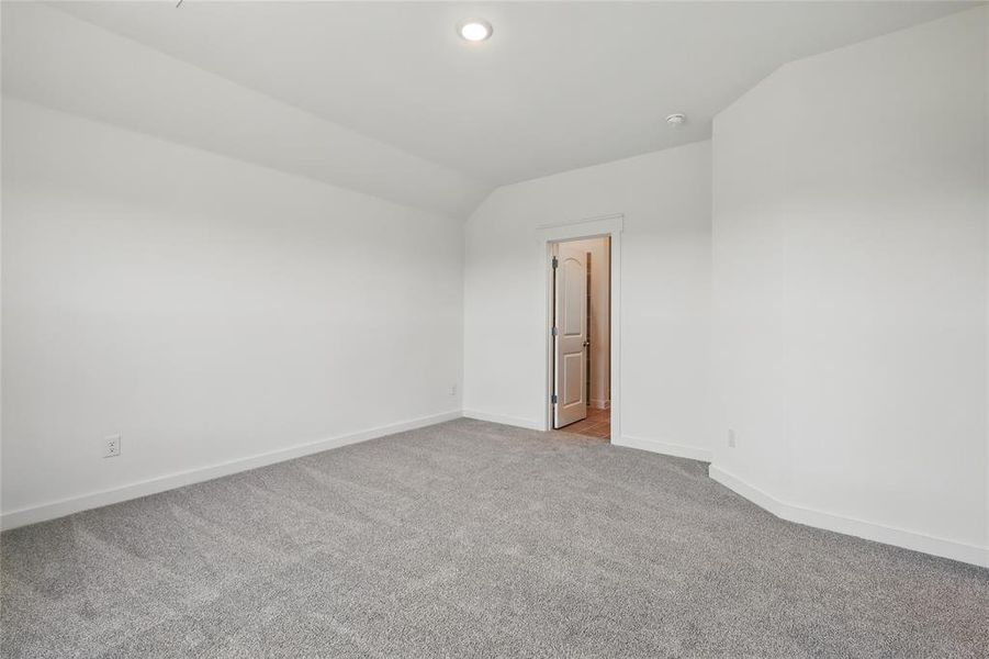 Carpeted empty room with baseboards, lofted ceiling, and recessed lighting Carpeted empty room with baseboards, lofted ceiling, and recessed lighting