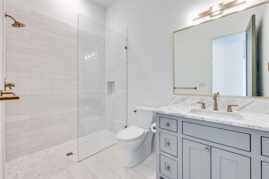 Bathroom with tile patterned flooring, toilet, vanity, and tiled shower