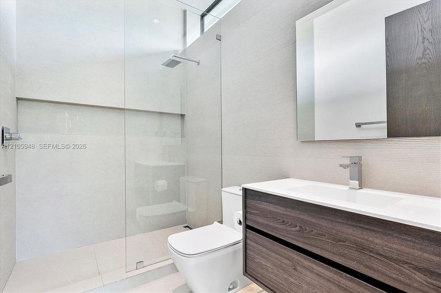 Modern floating vanity featuring wood-finish cabinetry, white countertop, integrated sink, and rectangular wall mirror