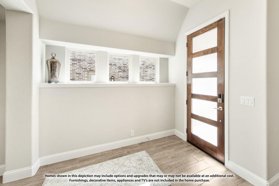 Entryway with wood and glass front door, vaulted ceiling, built-in shelf, and light wood-look floors Entryway with wood and glass front door, vaulted ceiling, built-in shelf, and light wood-look floors