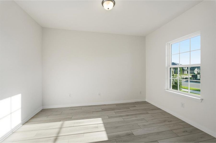 Room featuring light wood-finish flooring, white walls, and a single window with grids