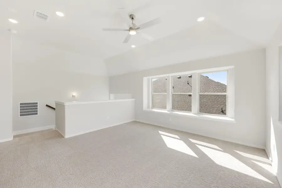 Bonus room with vaulted ceiling, ceiling fan, carpet flooring, and large window overlooking neighboring rooftop