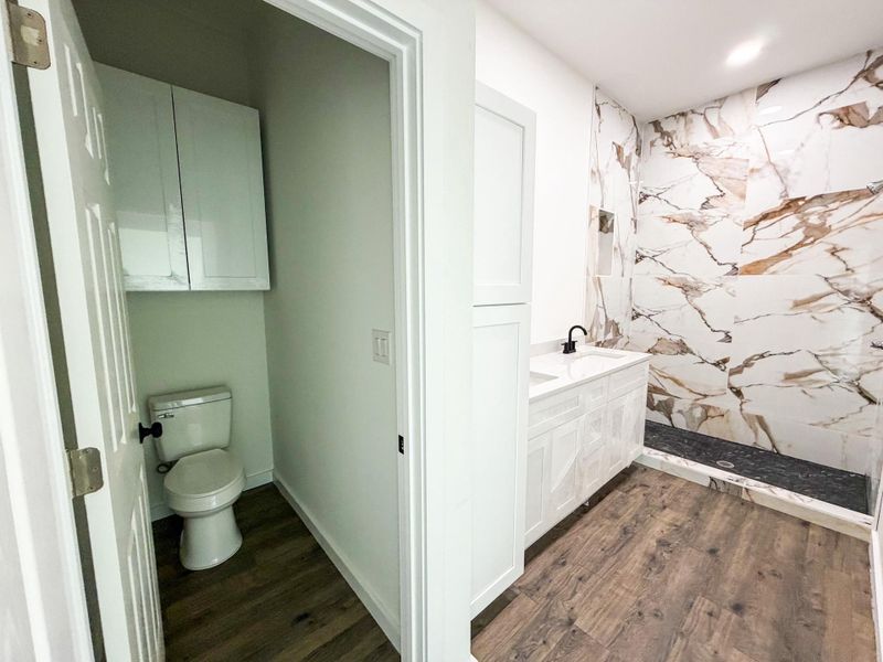 Bathroom featuring a large vanity with white cabinetry, a black faucet, and a stone-look countertop Bathroom featuring a large vanity with white cabinetry, a black faucet, and a stone-look countertop