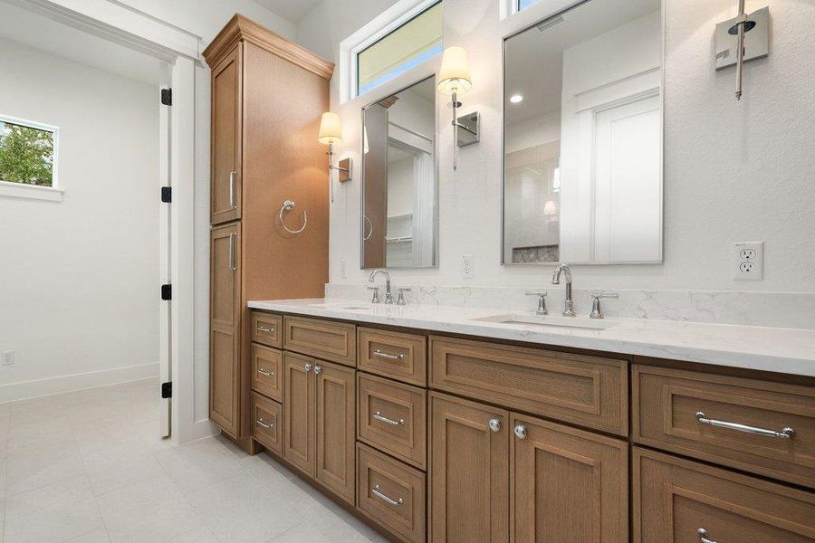 Bathroom featuring a double vanity with light wood cabinetry, white countertops, and dual mirrors with sconce lighting
