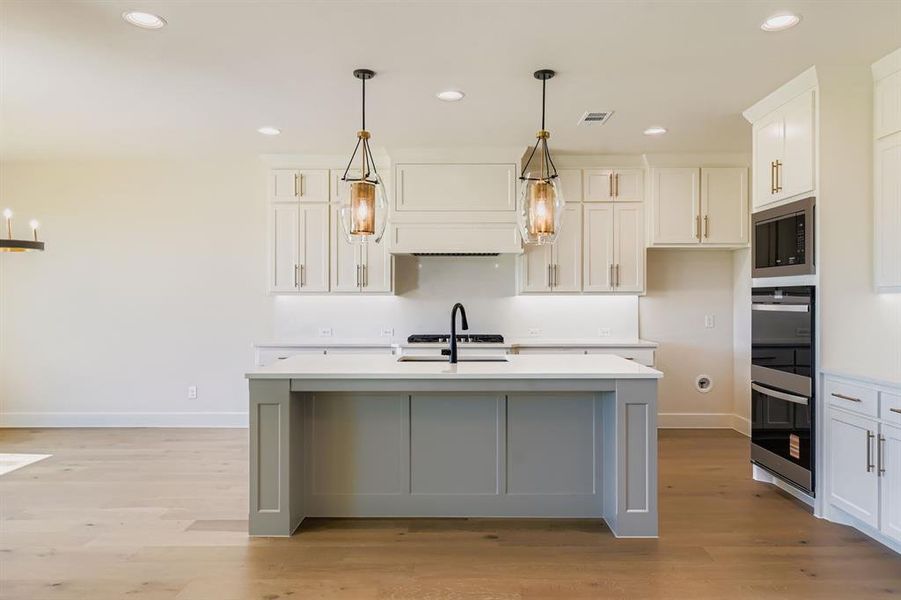 Kitchen with recessed lighting, light countertops, stainless steel appliances, and light wood-style flooring