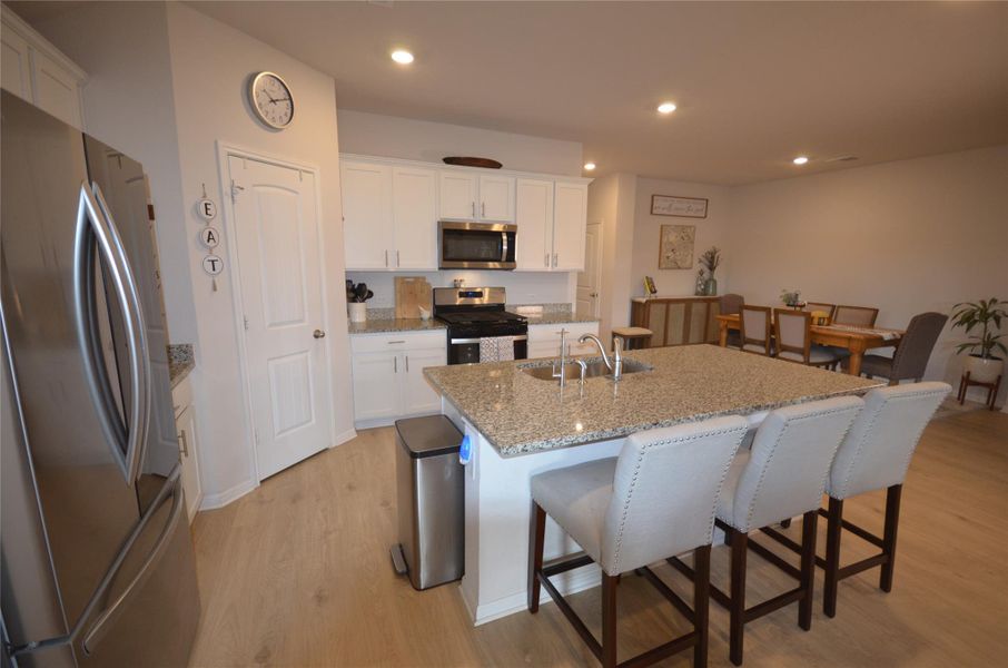 Kitchen with stainless steel appliances, light wood-type flooring, a kitchen breakfast bar, a kitchen island with sink, and recessed lighting Kitchen with stainless steel appliances, light wood-type flooring, a kitchen breakfast bar, a kitchen island with sink, and recessed lighting