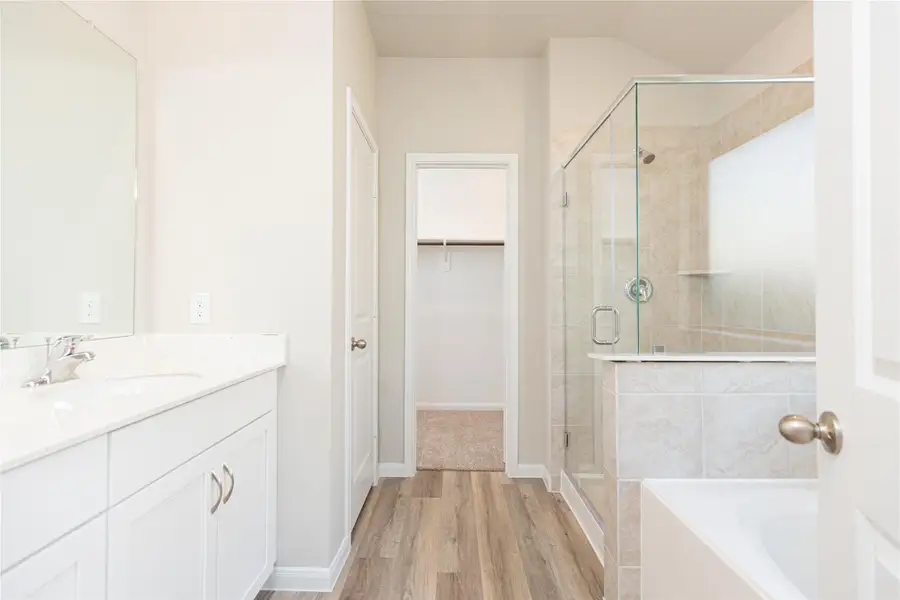 Escape to a spa-like oasis in this primary bathroom. Enjoy a walk-in shower with tile surround, a separate garden tub with custom detailing, and an elegant vanity featuring light countertops, modern hardware, and beautiful recessed lights. Experience luxury and relaxation in every detail Sample photo of completed home with similar floor plan. Actual colors and selections may vary.