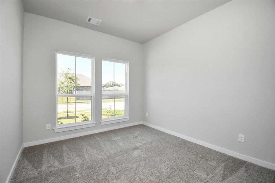 At the forefront, a refined guest suite. Features custom paint, expansive windows with privacy blinds, and premium carpet. Sample photo of completed home with similar floor plan. As-built interior colors and selections may vary.