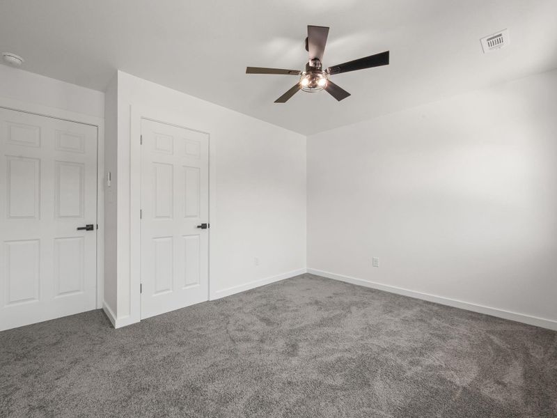 Room featuring white walls, gray carpet, and two white paneled doors with black hardware