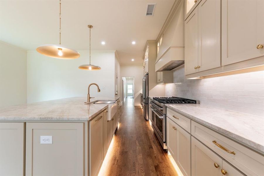 Gourmet kitchen featuring a large island, farmhouse sink, professional-grade range, stainless steel appliances, and under-cabinet lighting Gourmet kitchen featuring a large island, farmhouse sink, professional-grade range, stainless steel appliances, and under-cabinet lighting