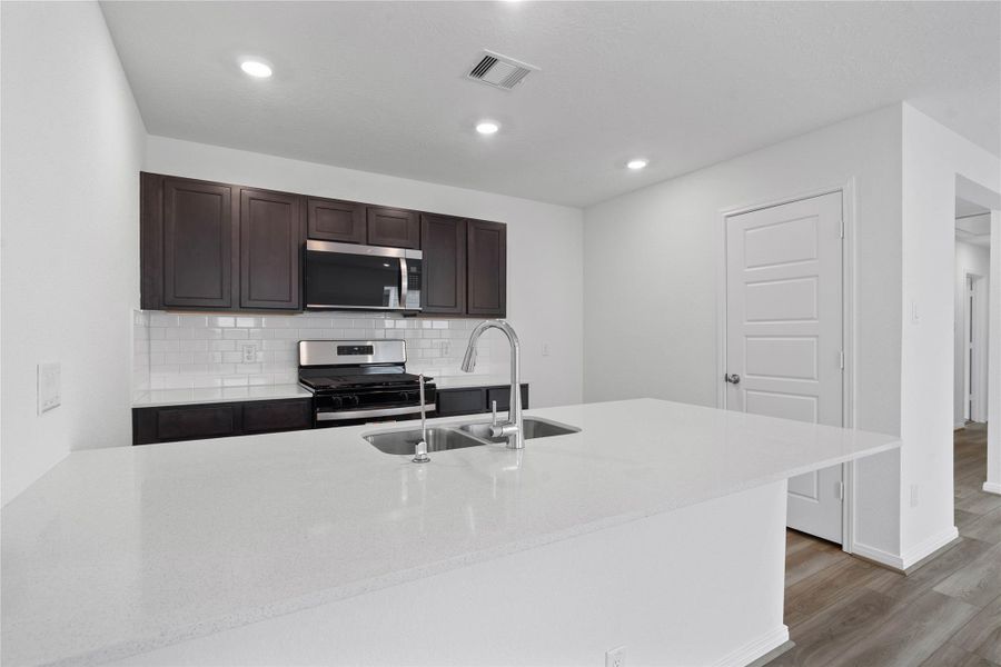 This spacious kitchen features this long quartz countertop in Blanco Maple and added breakfast bar.