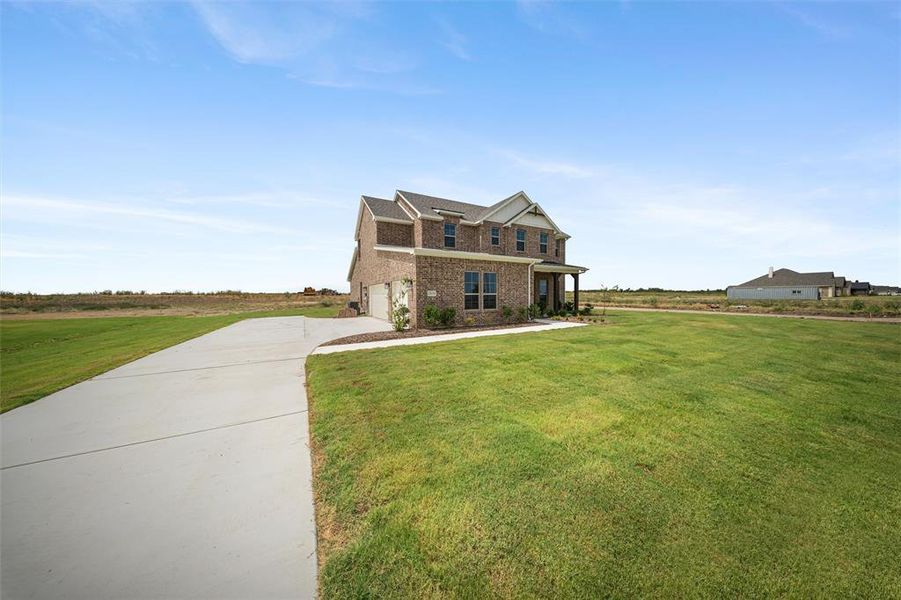 View of front of home with brick siding, driveway, an attached garage, and a front yard View of front of home with brick siding, driveway, an attached garage, and a front yard