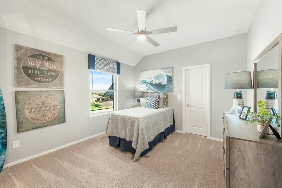 Bedroom with carpet, ceiling fan, vaulted ceiling, surf-themed wall art, and a window with blue valance