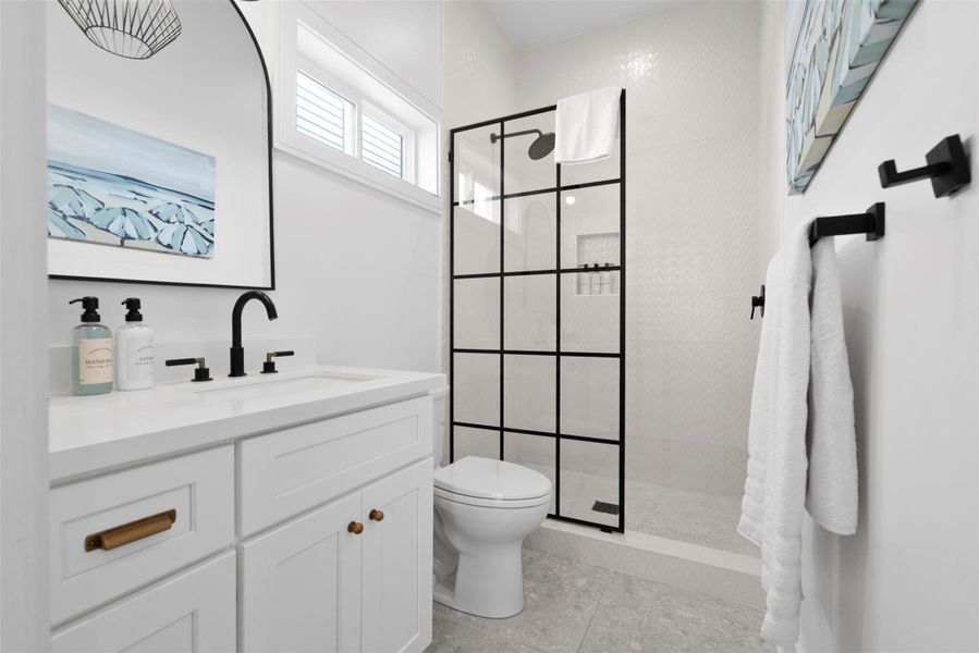 Connected to the secondary bedroom, this private en suite blends form and function with a sleek bold black fixtures, a modern toilet, and a minimalist vanity featuring a built-in sink and storage drawers—perfect for a polished, coastal retreat. Connected to the secondary bedroom, this private en suite blends form and function with a sleek bold black fixtures, a modern toilet, and a minimalist vanity featuring a built-in sink and storage drawers—perfect for a polished, coastal retreat.