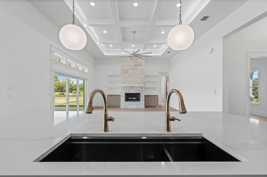 Kitchen with light stone countertops, open floor plan, coffered ceiling, beamed ceiling, and pendant lighting Kitchen with light stone countertops, open floor plan, coffered ceiling, beamed ceiling, and pendant lighting