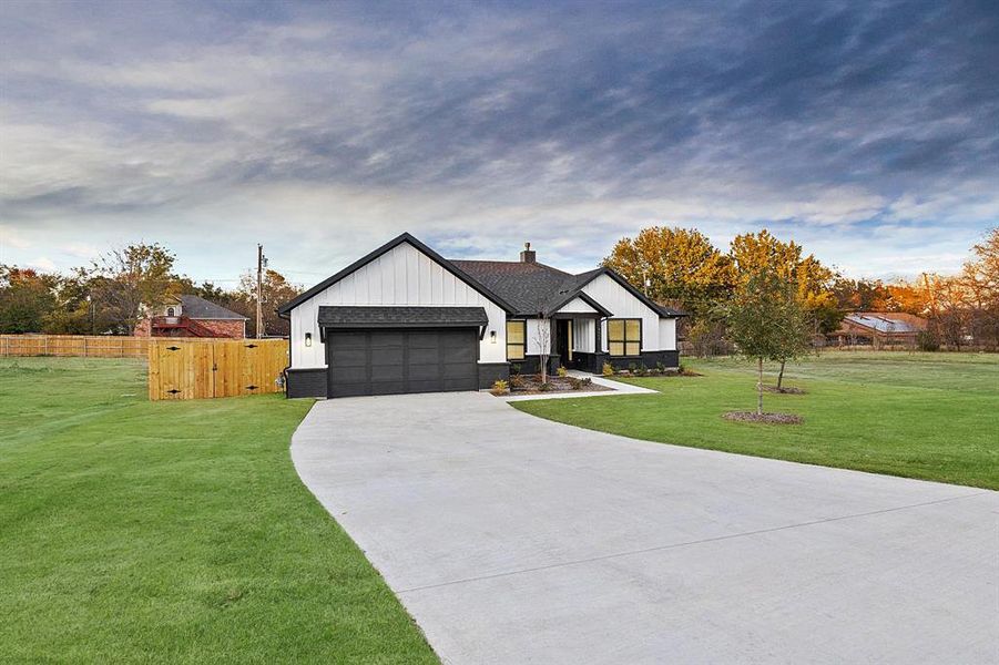 Modern inspired farmhouse with driveway, a front lawn, a garage, roof with shingles, and board and batten siding