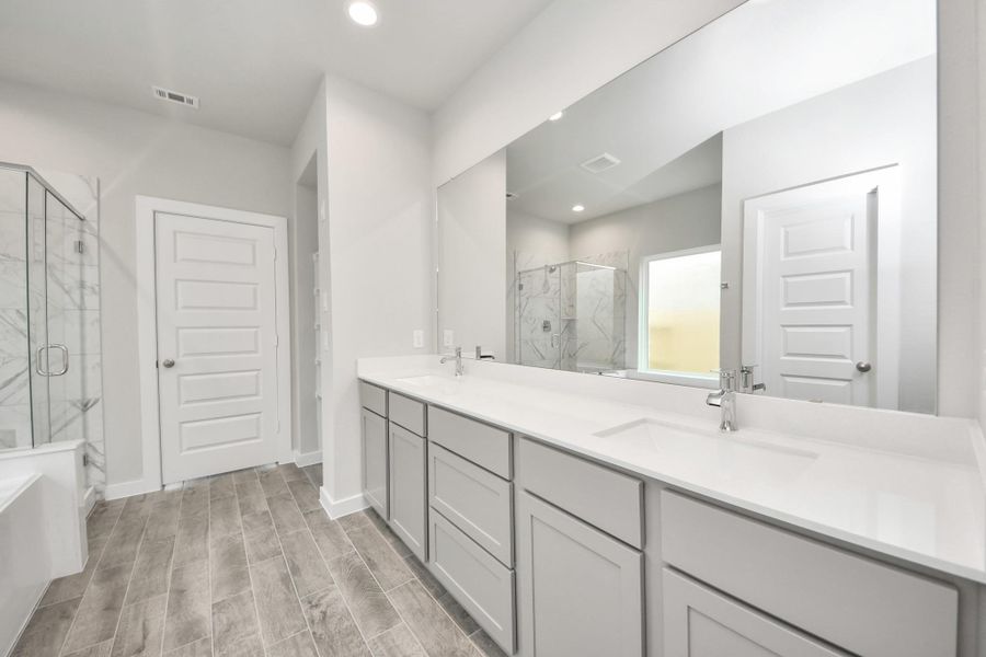 Elevate your daily routine at the elegant vanity, now equipped with double sinks, light countertops, modern hardware, and beautiful recessed lights. Sample photo of completed home with similar floor plan. Actual colors and selections may vary.