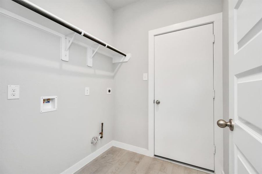 Located on first floor, a stylish laundry room where practicality meets a contemporary aesthetic. The dark finishes lend a sophisticated touch, creating a space that is both functional and visually appealing. Both electric and gas connections available. Sample photo of completed home with similar floor plan. As-built interior colors and selections may vary.