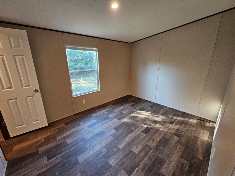 Unfurnished bedroom with dark wood-type flooring, a decorative wall, recessed lighting, and a textured ceiling Unfurnished bedroom with dark wood-type flooring, a decorative wall, recessed lighting, and a textured ceiling