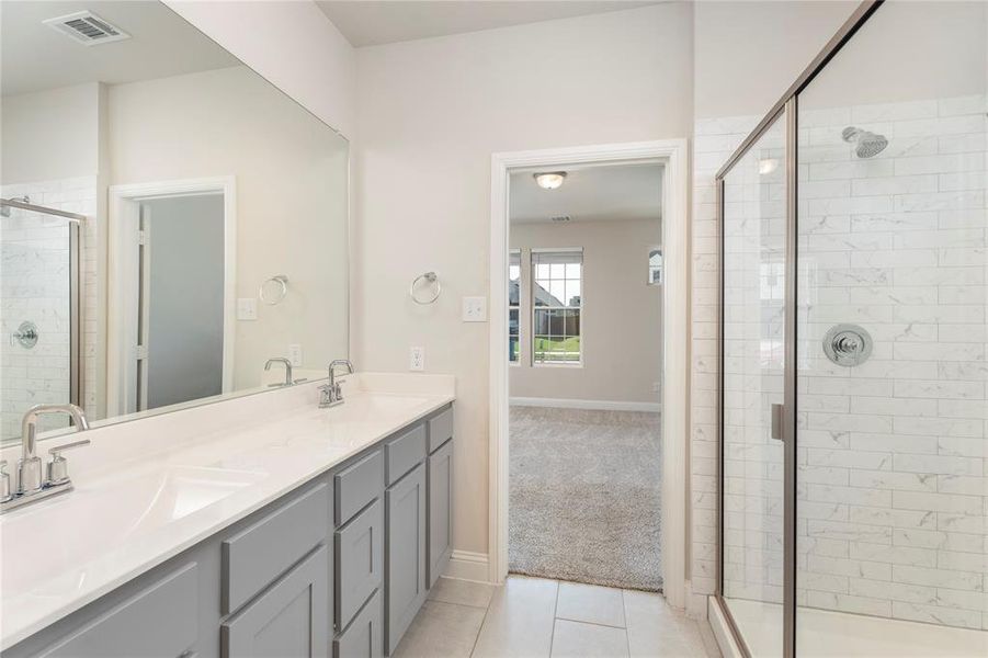 Full bath featuring double vanity, a stall shower, and tile patterned floors