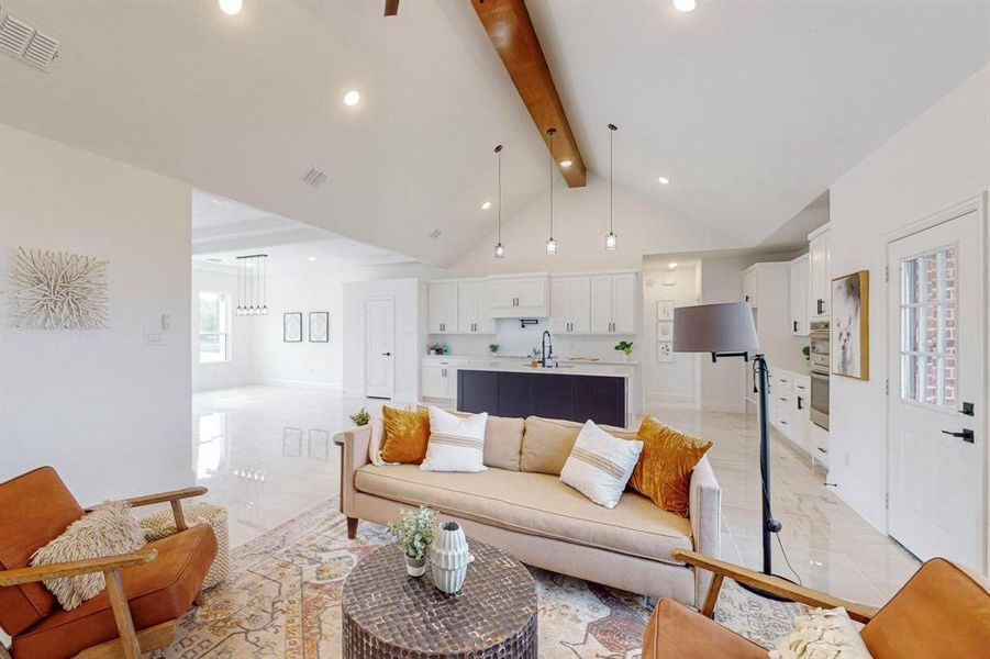 Living room featuring beamed ceiling, sink, and high vaulted ceiling