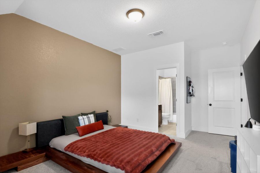Carpeted room featuring a neutral accent wall, white trim, and a high ceiling Carpeted room featuring a neutral accent wall, white trim, and a high ceiling